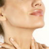 Close-up of a woman's chin and neck with hands resting on the throat, highlighting smooth skin.