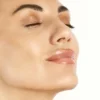 Close-up of a woman with smooth skin, eyes closed, and glossy pink lips.