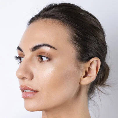 Close-up profile of a woman with dark hair tied back, showing smooth skin and neutral makeup to the left side.