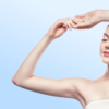 Close-up of a woman with arms raised and hands intertwined above her head, against a pale blue background.
