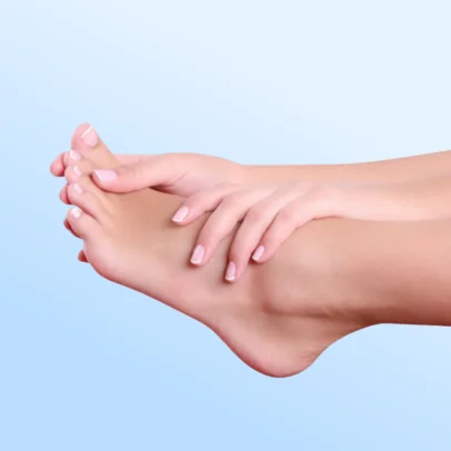 Bare foot being massaged by hands against a soft blue gradient background, suggesting a spa or foot care scene.