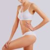 Woman wearing a white sports bra and matching briefs, posing with hand on hip.