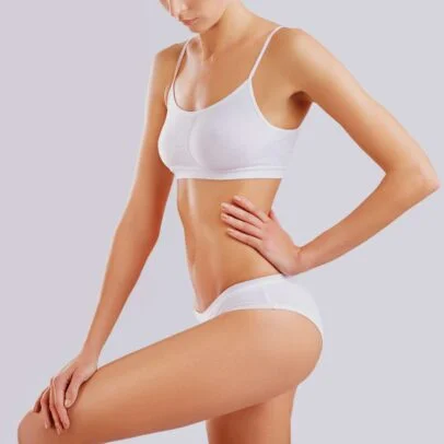 Woman wearing a white sports bra and matching briefs, posing with hand on hip.