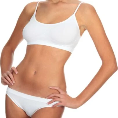 Woman wearing a white bra and matching briefs, standing with hands on her hips.