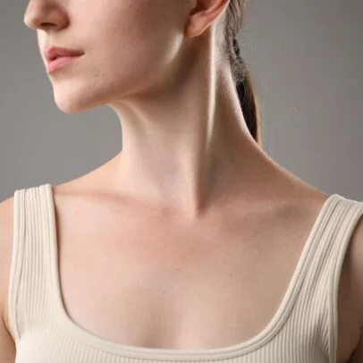 Close-up profile of a woman's neck and lower face, wearing a cream ribbed tank top.