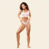 Woman in a white sports bra and high-cut underwear striking a dynamic pose against a pale beige background.