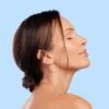 Side profile of a woman with eyes closed against a light blue background, conveying calm and wellness.