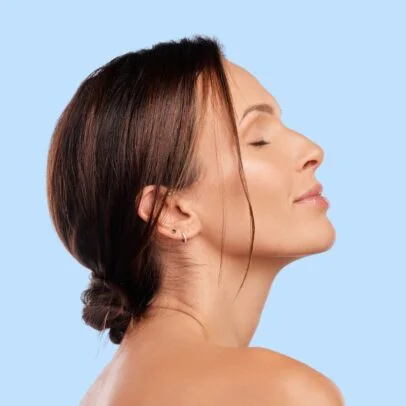 Side profile of a woman with eyes closed against a light blue background, conveying calm and wellness.